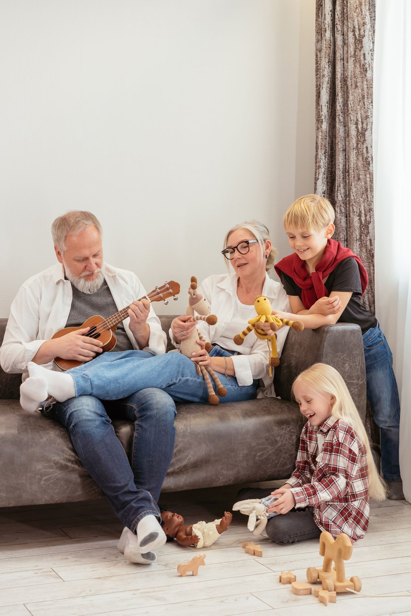 Grandparents on a sofa playing with their grandchildren