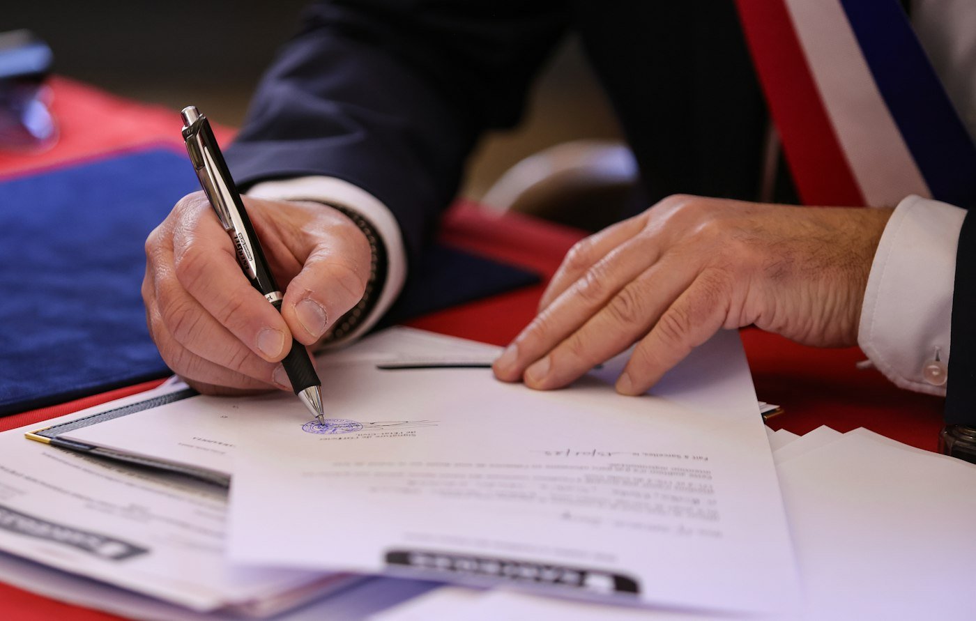 Close-up of a hand signing a document with a pen